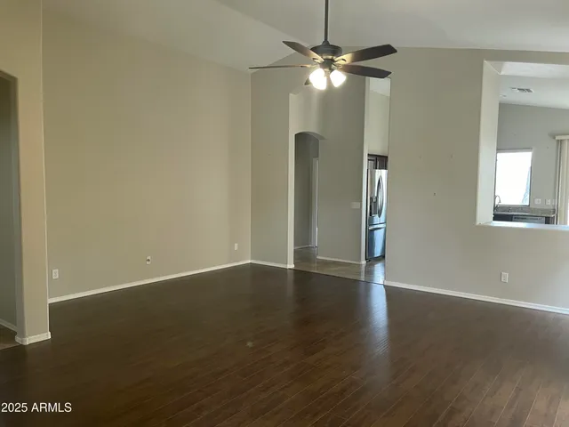 an empty room with wooden floor fan and window
