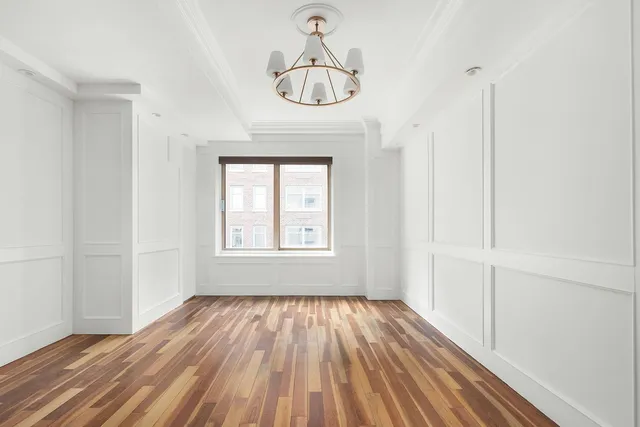 a very nice looking room with wooden floor a ceiling fan and window