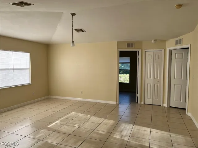a view of an empty room with window and cabinet