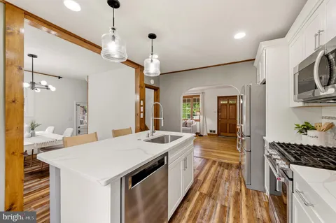 a kitchen with a sink appliances wooden floor and a window