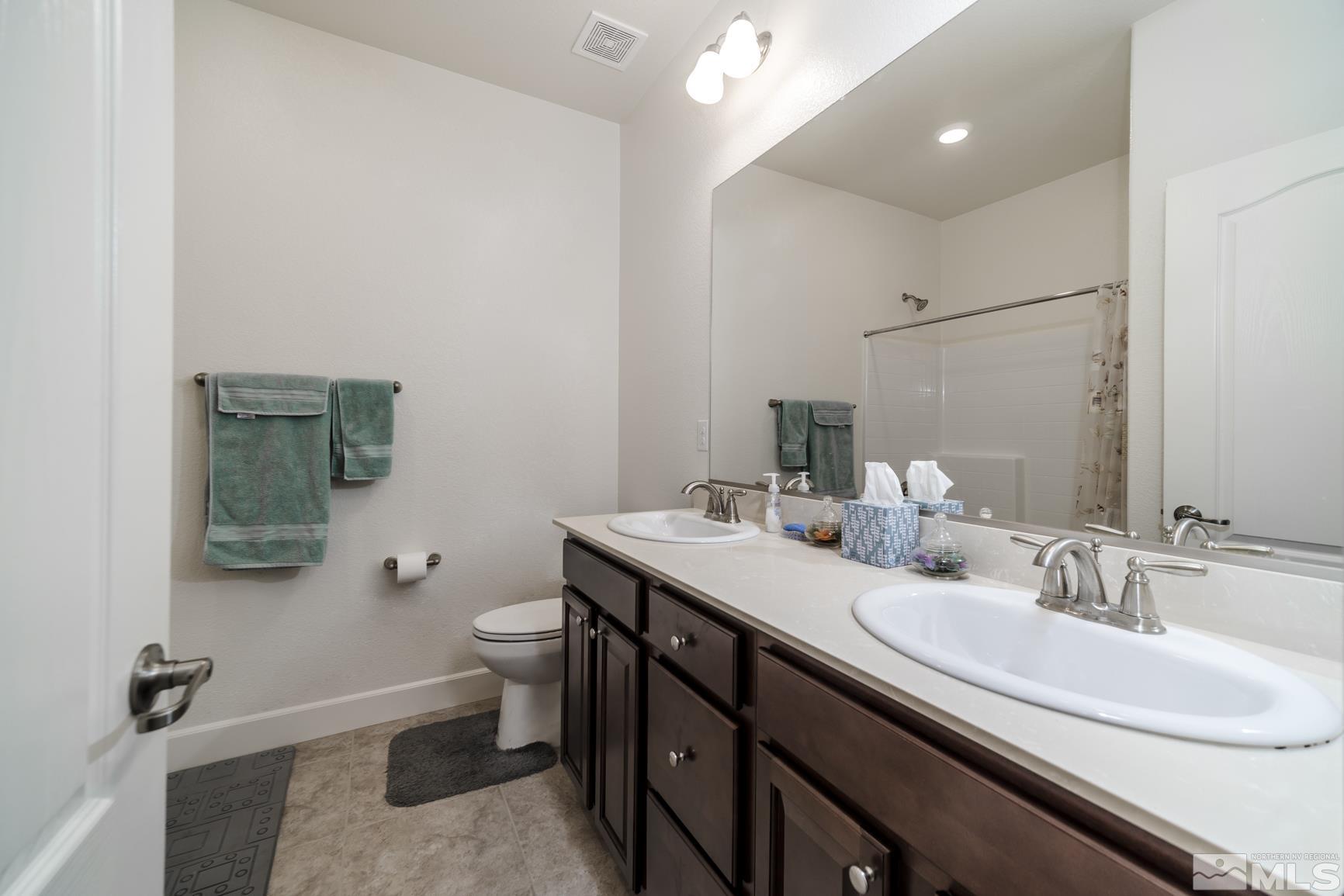 6758 Eagle Peak Drive Carson City, NV 89701 - Photo 17 of 28 a bathroom with a granite countertop sink a toilet and a mirror