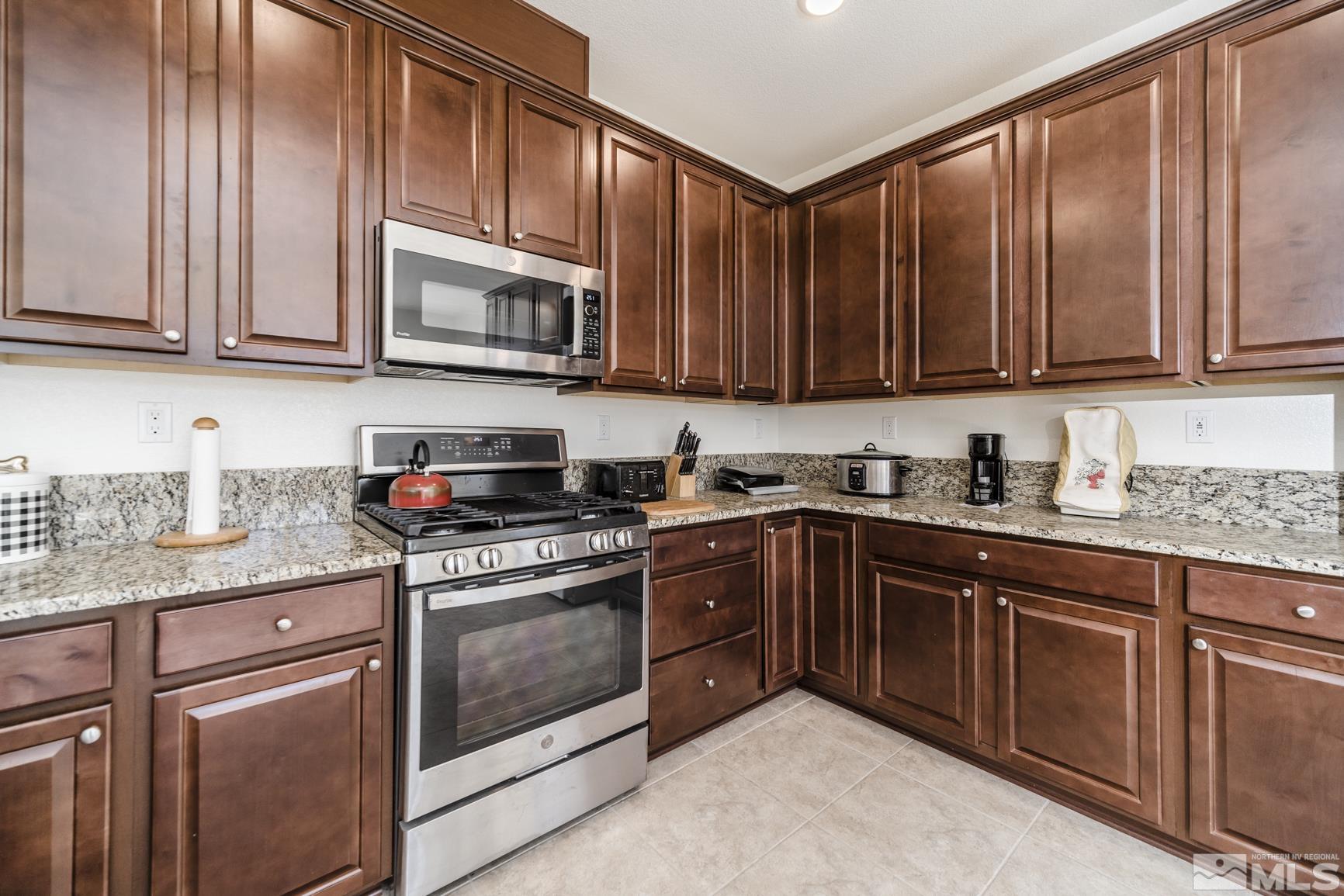 6758 Eagle Peak Drive Carson City, NV 89701 - Photo 3 of 28 a kitchen with stainless steel appliances granite countertop wooden cabinets a stove top oven a sink and dishwasher