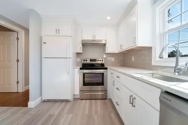 a kitchen with granite countertop white cabinets and white appliances