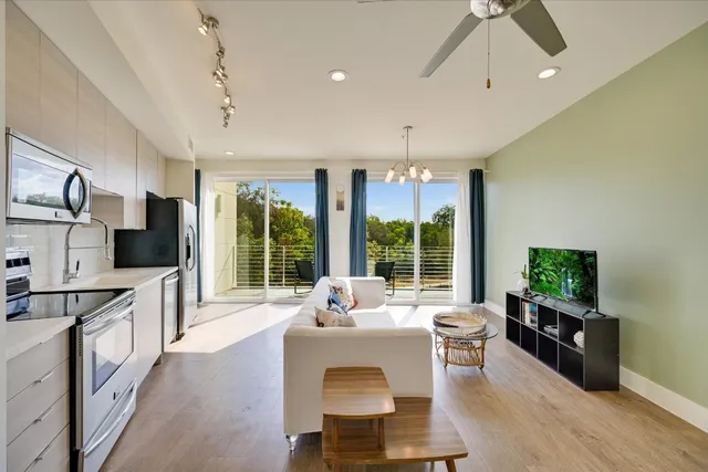 a living room with furniture a flat screen tv and a large window