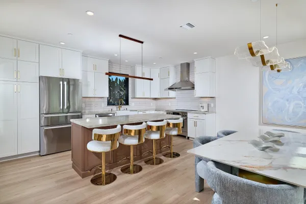 a kitchen with stainless steel appliances granite countertop a sink a stove a refrigerator and island with wooden floor