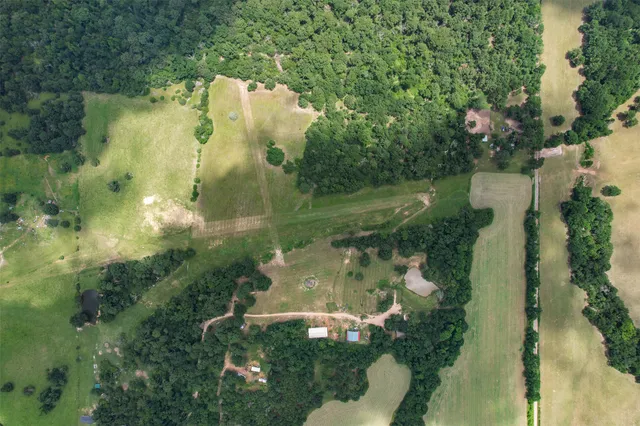 an aerial view of a residential houses with outdoor space and trees