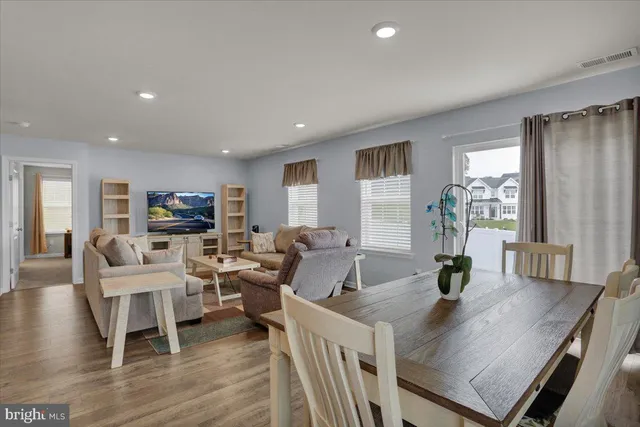 a living room with furniture kitchen view and a wooden floor