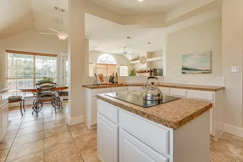 a kitchen with kitchen island granite countertop a table chairs sink and cabinets