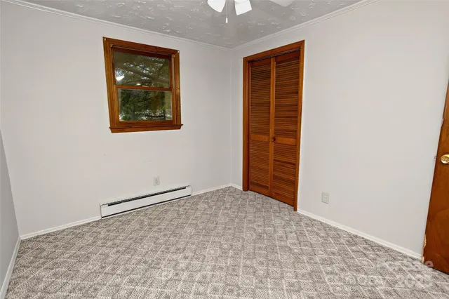 an empty room with a chandelier fan and windows