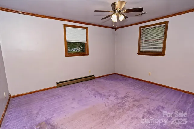 an empty room with chandelier fan and windows