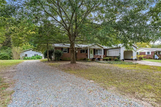 a front view of a house with a garden and trees