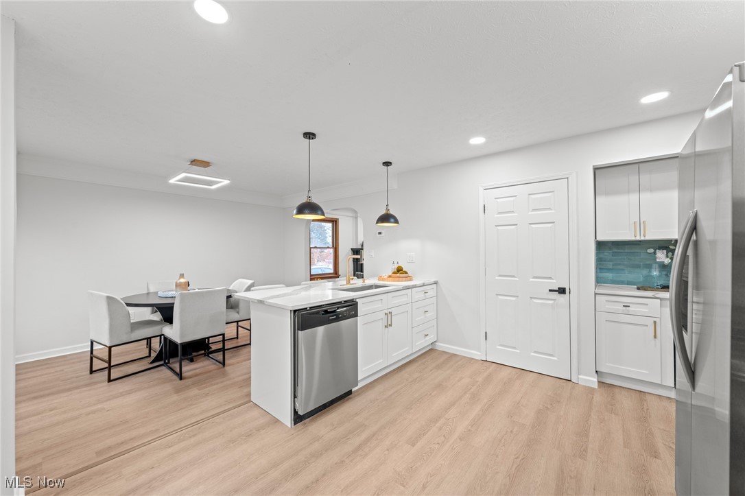 5266 Wilson Mills Road Cleveland, OH 44143 - Photo 19 of 50 Kitchen with a peninsula, hanging light fixtures, appliances with stainless steel finishes, white cabinets, and light wood finished floors