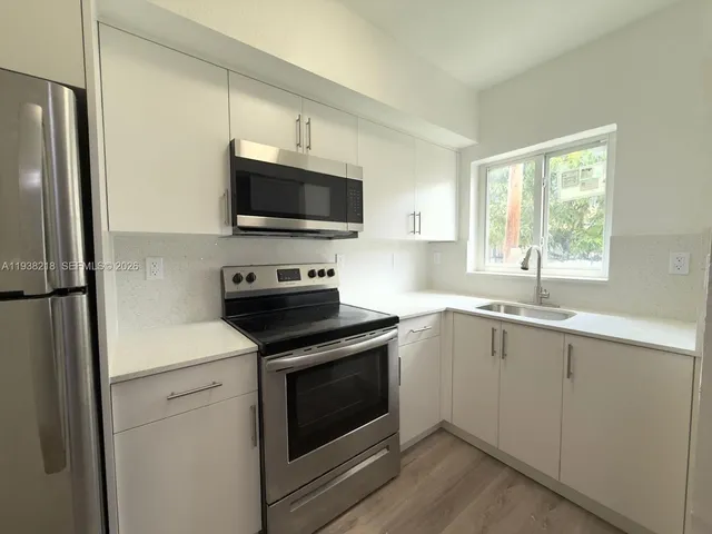 a kitchen with a stove a microwave and windows