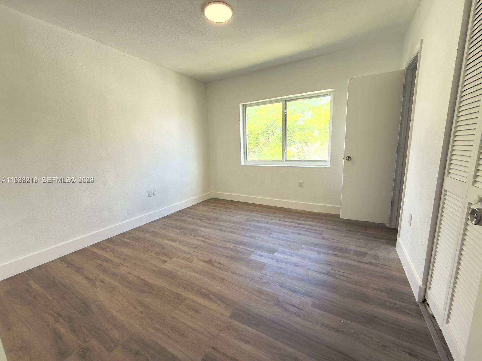 424 Northwest 84th Street, Unit 424 Miami, FL 33150 - Photo 9 of 15 an empty room with wooden floor and windows
