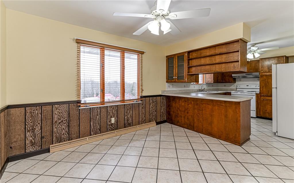 830 Hartzell School Road New Brighton, PA 15066 - Photo 7 of 31 a kitchen with stainless steel appliances a large counter top a stove a chimney a sink and a window
