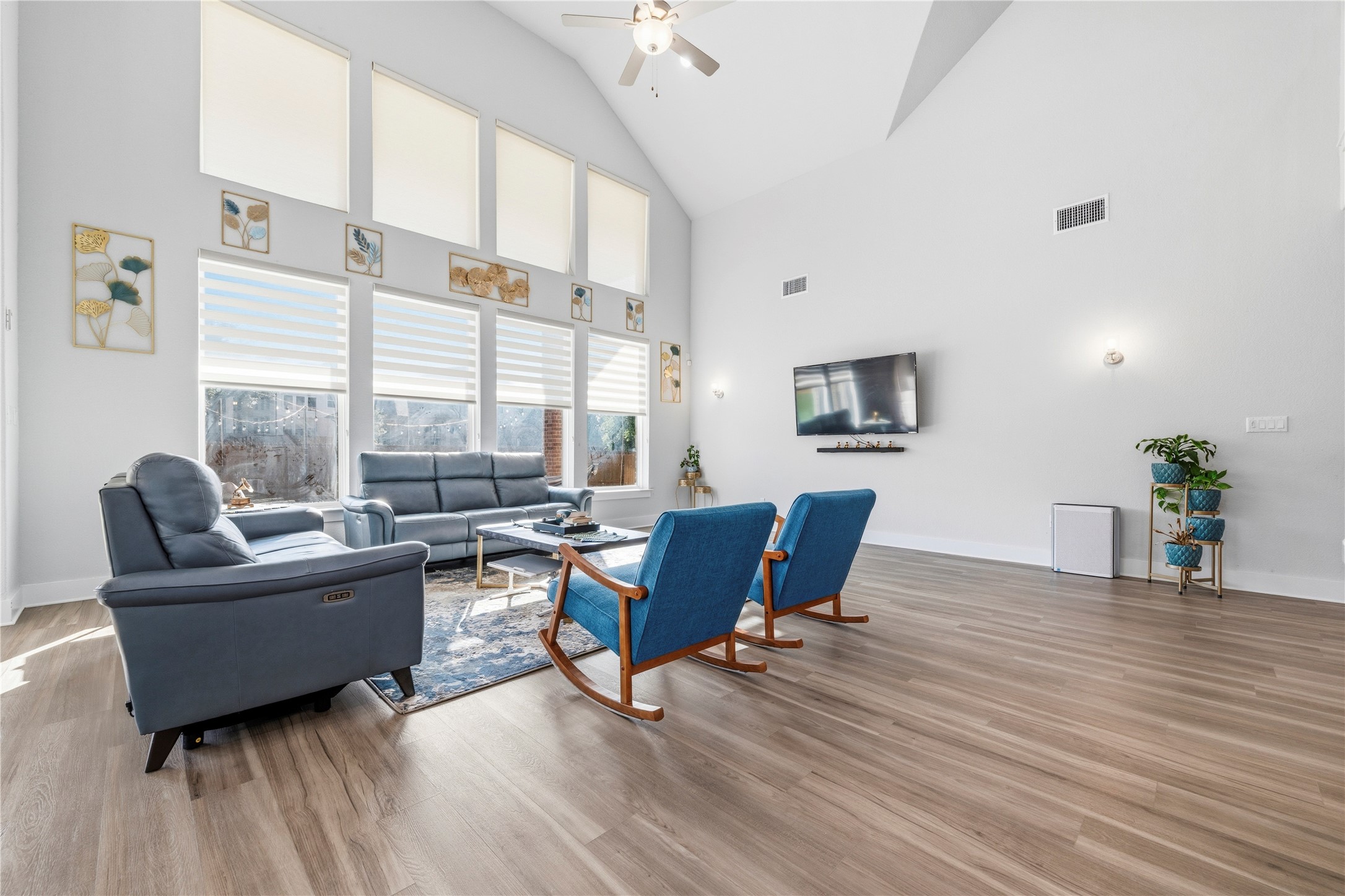 105 Autumn Oak Way Georgetown, TX 78628 - Photo 15 of 40 Spacious living area featuring a vaulted ceiling with a fan, wood-finish flooring, and a bank of windows with custom window treatments