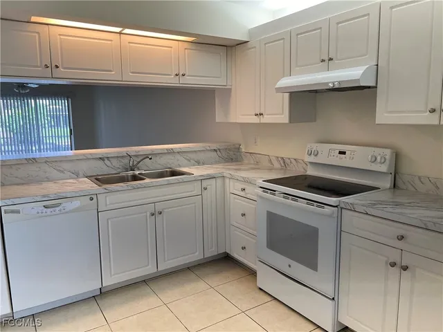 a kitchen with granite countertop white cabinets and white appliances
