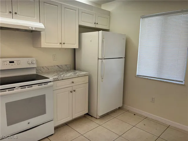 a kitchen with appliances a refrigerator and cabinets