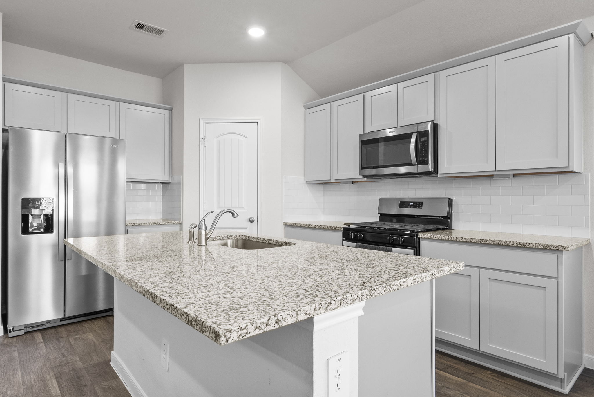 320 Darwin Place Lockhart, TX 78644 - Photo 2 of 31 Kitchen featuring stainless steel appliances, dark wood finished floors, backsplash, light stone countertops, and a center island with sink