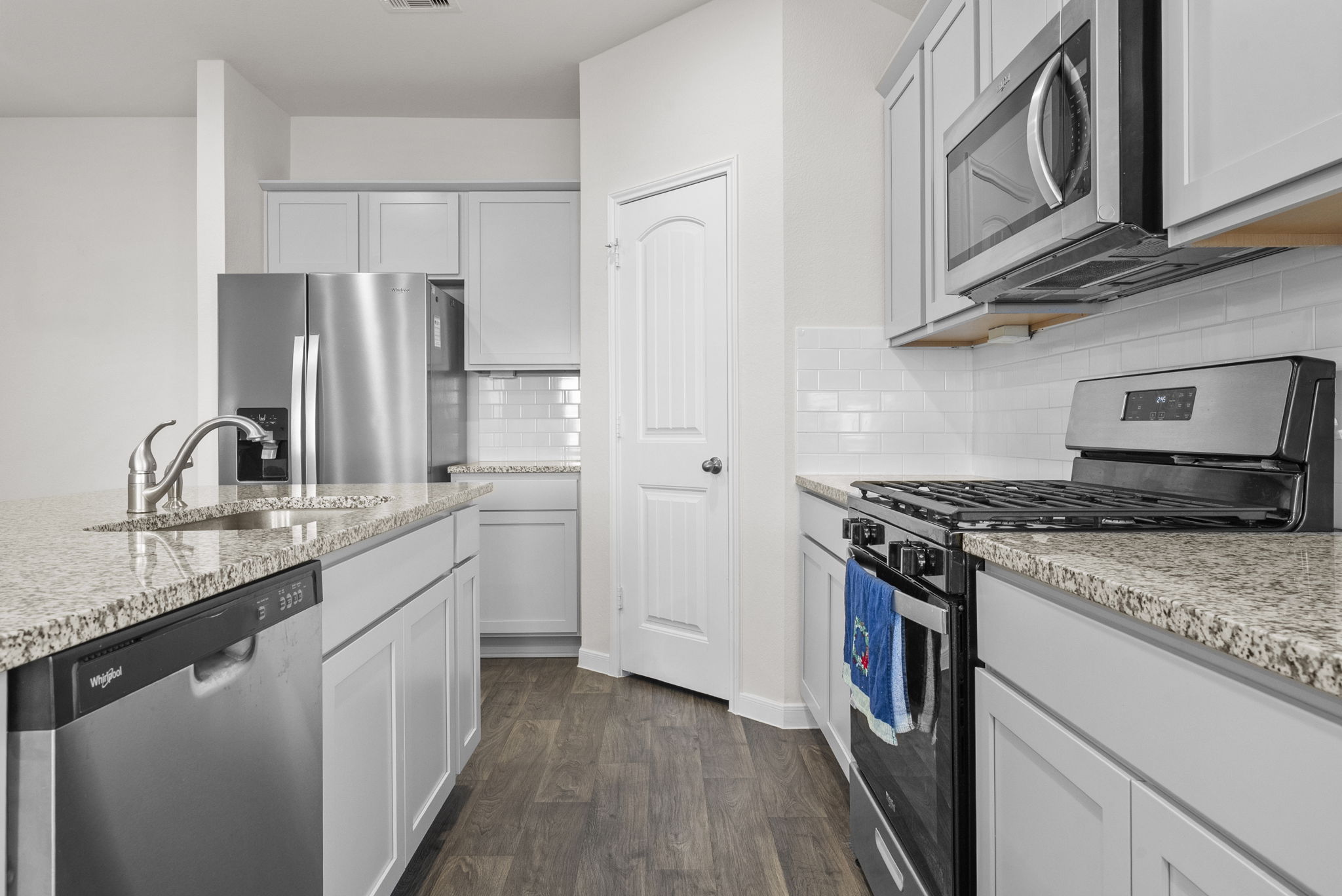 320 Darwin Place Lockhart, TX 78644 - Photo 4 of 31 Kitchen featuring stainless steel appliances, dark wood-type flooring, light stone counters, and decorative backsplash