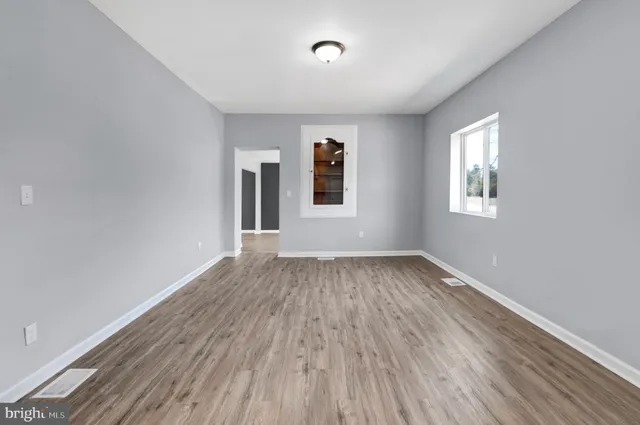 a view of an empty room with wooden floor and window