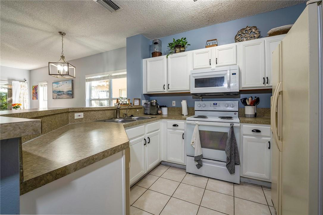 6960 Brook Hollow Road Lake Worth, FL 33467 - Photo 6 of 24 a kitchen with granite countertop white cabinets and white appliances
