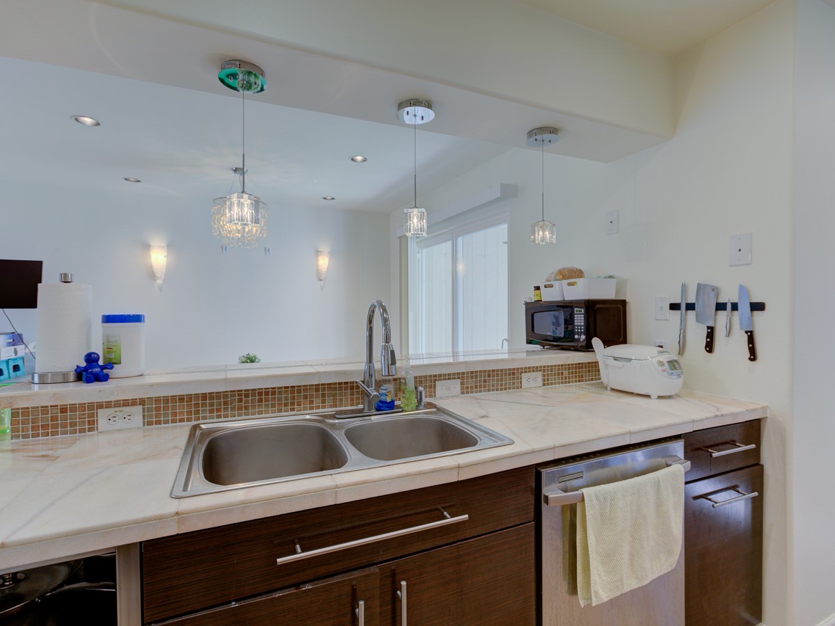 710 Castle Ridge Road, Unit B Austin, TX 78746 - Photo 8 of 27 A well-appointed kitchen features rich cabinetry, dual sinks, and modern lighting.