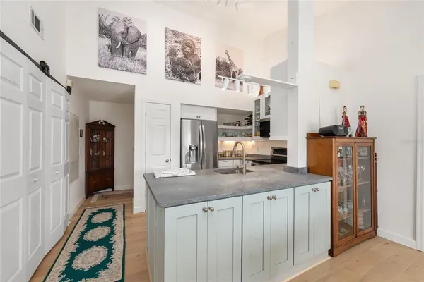 a kitchen with stainless steel appliances granite countertop a sink a stove a refrigerator a dining table and chairs with wooden floor