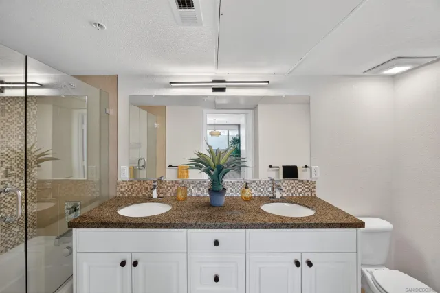 a bathroom with a granite countertop sink a toilet and a mirror