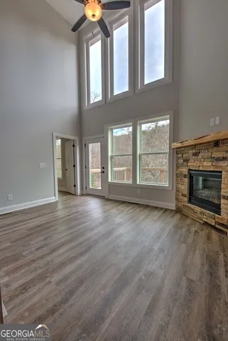 an empty room with wooden floor fireplace and windows