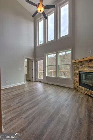 an empty room with wooden floor fireplace and windows