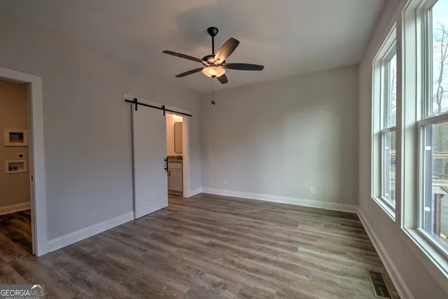 a view of empty room with wooden floor and fan