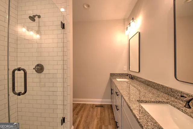 a bathroom with a granite countertop shower a sink and a mirror