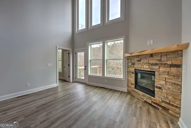 an empty room with wooden floor fireplace and windows