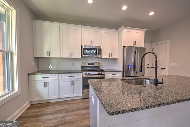 a kitchen with kitchen island granite countertop a stove a sink and a refrigerator