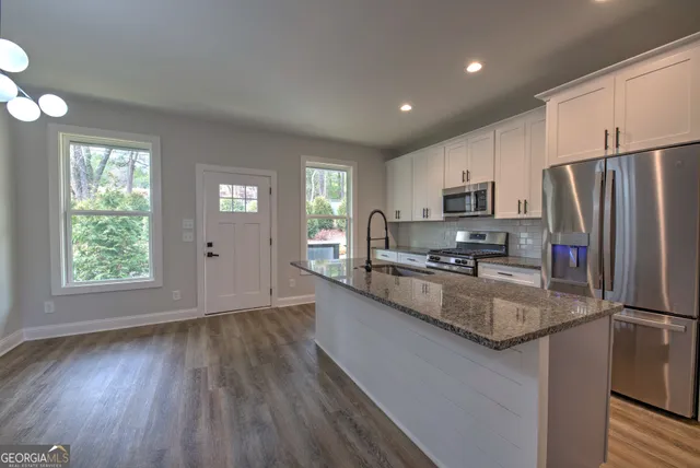 a large kitchen with a center island wooden floor stainless steel appliances and windows