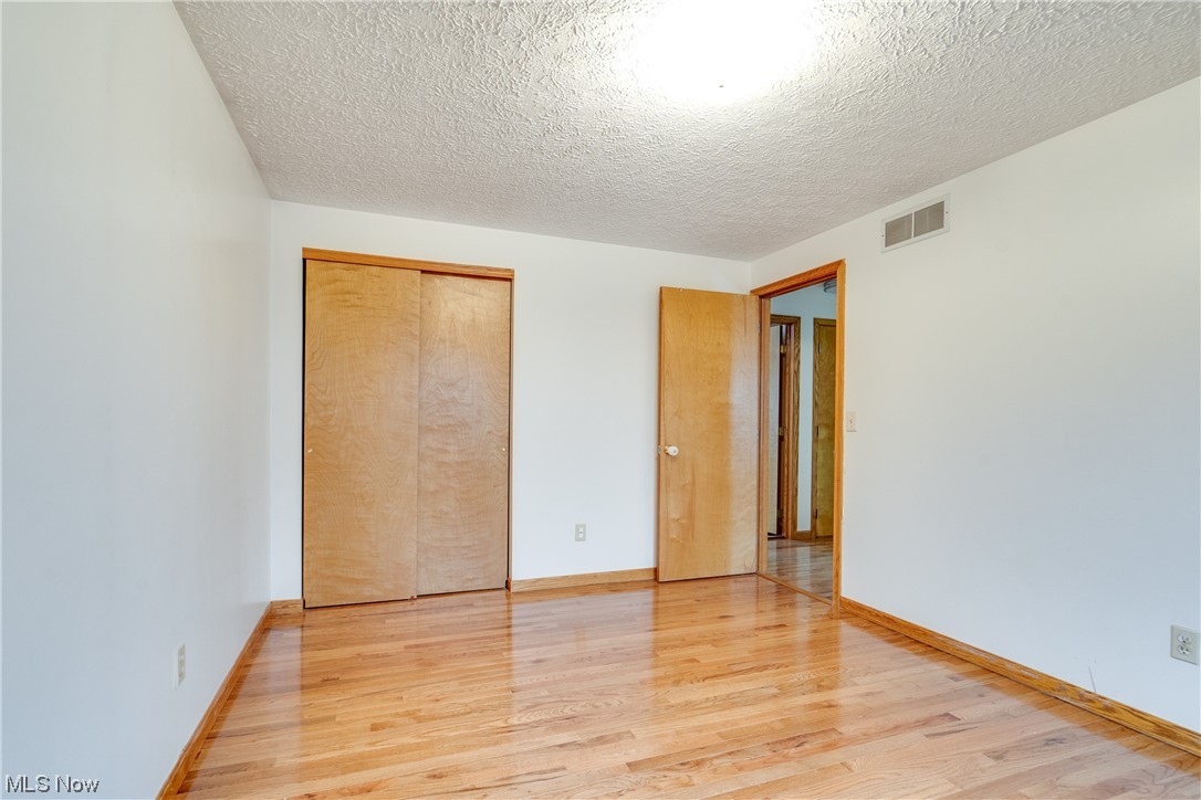 5303 Laubert Road Atwater, OH 44201 - Photo 24 of 37 Unfurnished bedroom featuring a closet, light hardwood / wood-style floors, and a textured ceiling