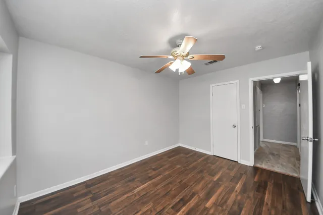a view of a room with wooden floor and a ceiling fan
