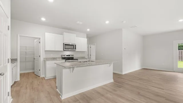 a kitchen with stainless steel appliances granite countertop a stove top oven a sink and a refrigerator