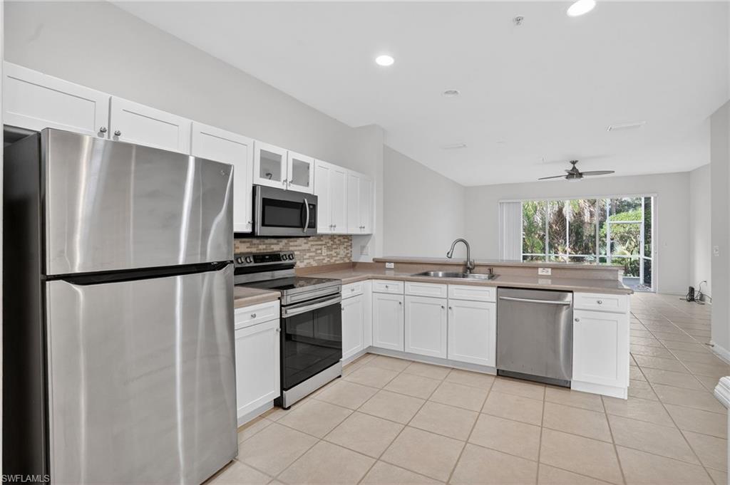 15995 Caldera Lane, Unit 69 Naples, FL 34110 - Photo 11 of 27 Kitchen with stainless steel appliances, white cabinets, backsplash, ceiling fan, and a peninsula