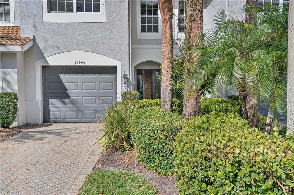 15995 Caldera Lane, Unit 69 Naples, FL 34110 - Photo 2 of 27 Doorway to property featuring stucco siding, decorative driveway, and a garage