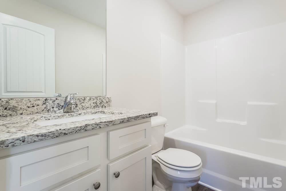 6913 Point Bar Place Raleigh, NC 27616 - Photo 18 of 23 a bathroom with a granite countertop toilet a sink and a bathtub