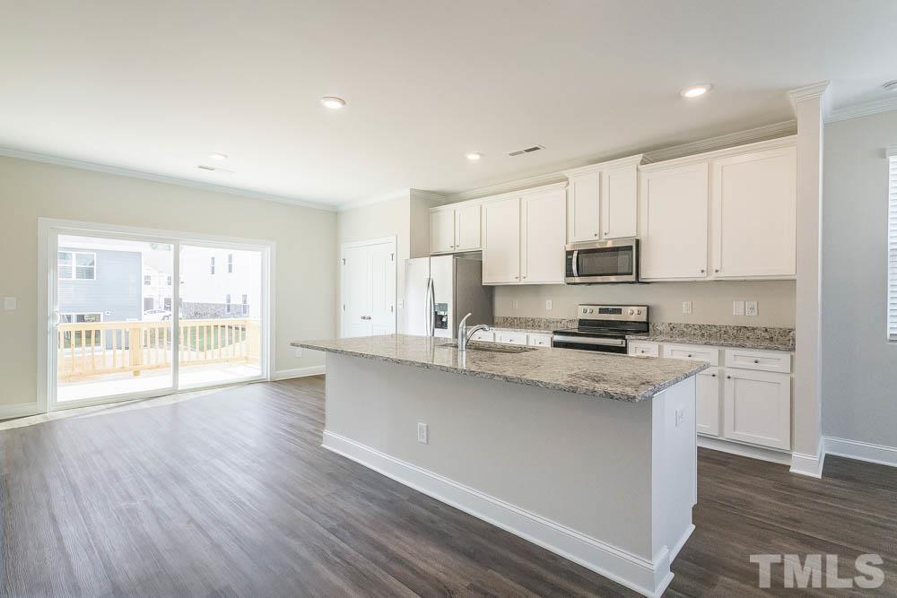 6913 Point Bar Place Raleigh, NC 27616 - Photo 7 of 23 a kitchen with stainless steel appliances granite countertop a stove a sink a refrigerator white cabinets and a wooden floor