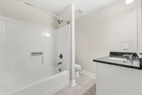 a bathroom with a granite countertop sink a toilet and shower