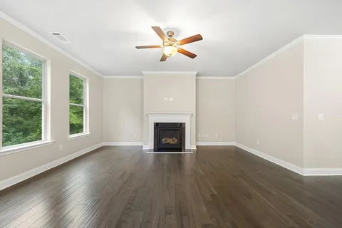 an empty room with wooden floor a fireplace and windows