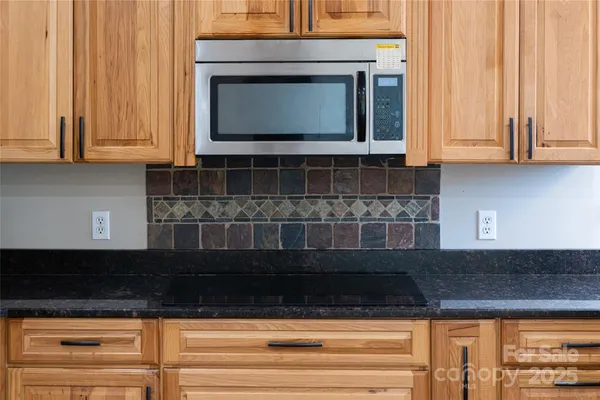 a kitchen with granite countertop white cabinets and black appliances