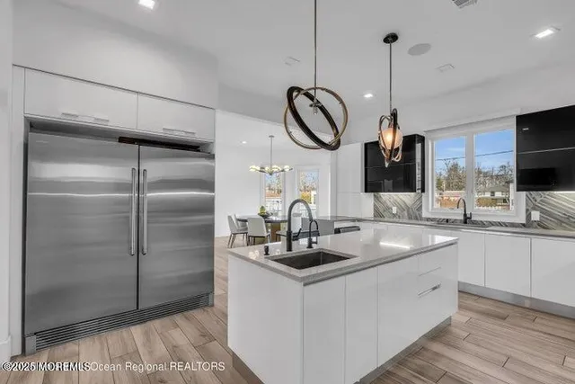 a kitchen with stainless steel appliances granite countertop a sink a refrigerator and a wooden floor