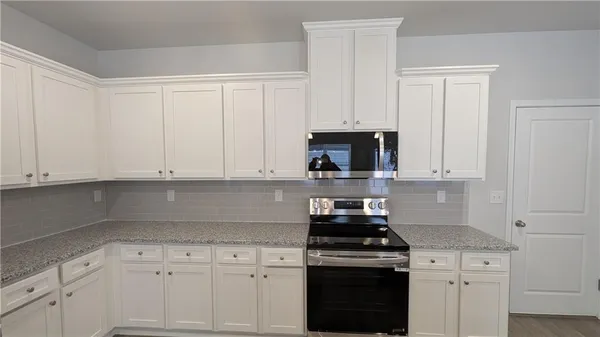 a kitchen with white cabinets and appliances