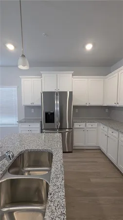 a kitchen with a refrigerator a sink and white cabinets