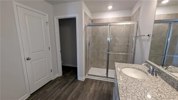 a bathroom with a granite countertop sink a mirror and shower